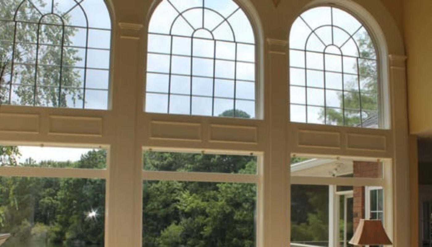 Floor-to-ceiling window wall with arched transoms overlooking a Lowcountry lake