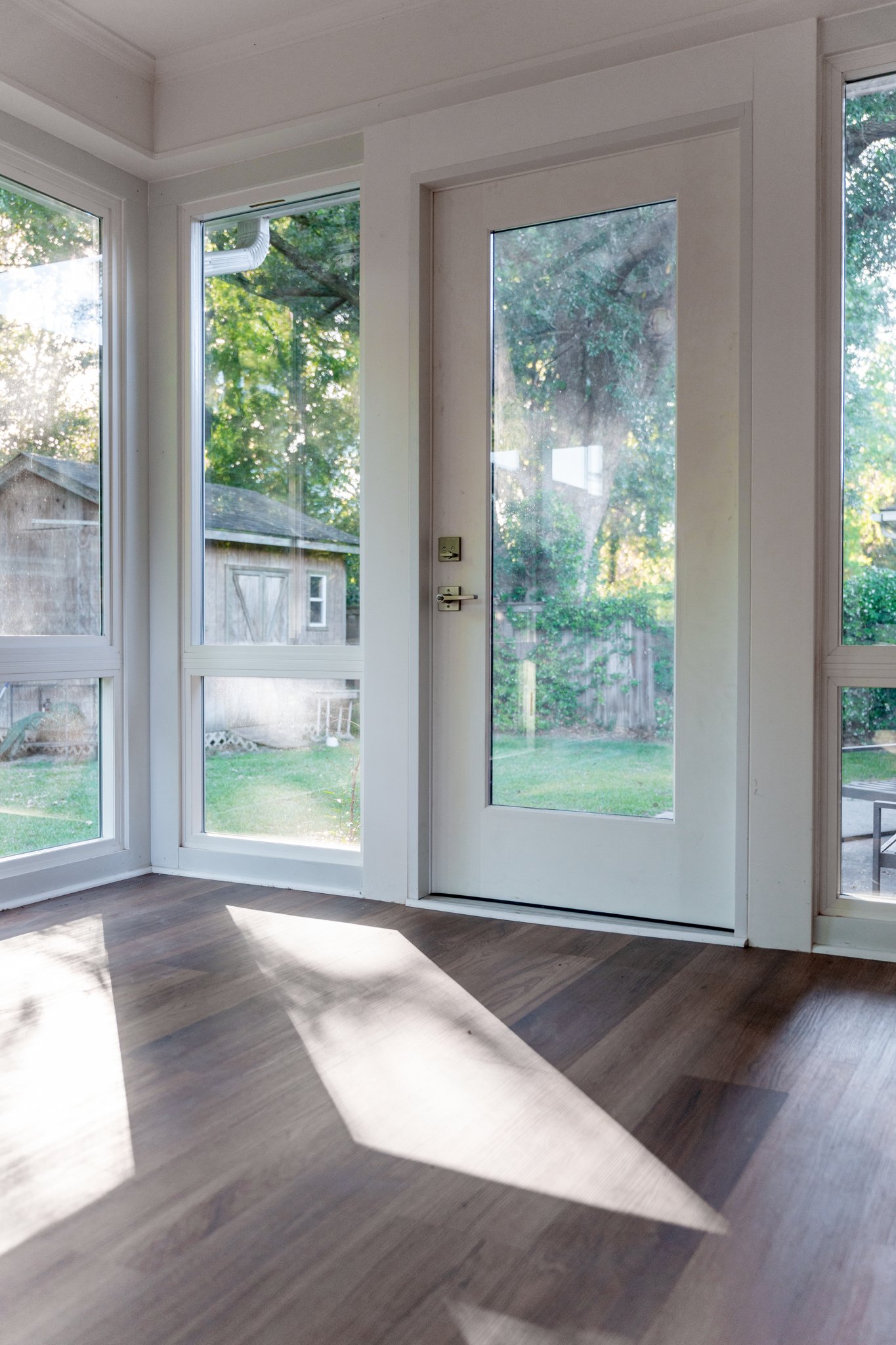 Interior corner with the glass door back into the house, afternoon light across the floor.