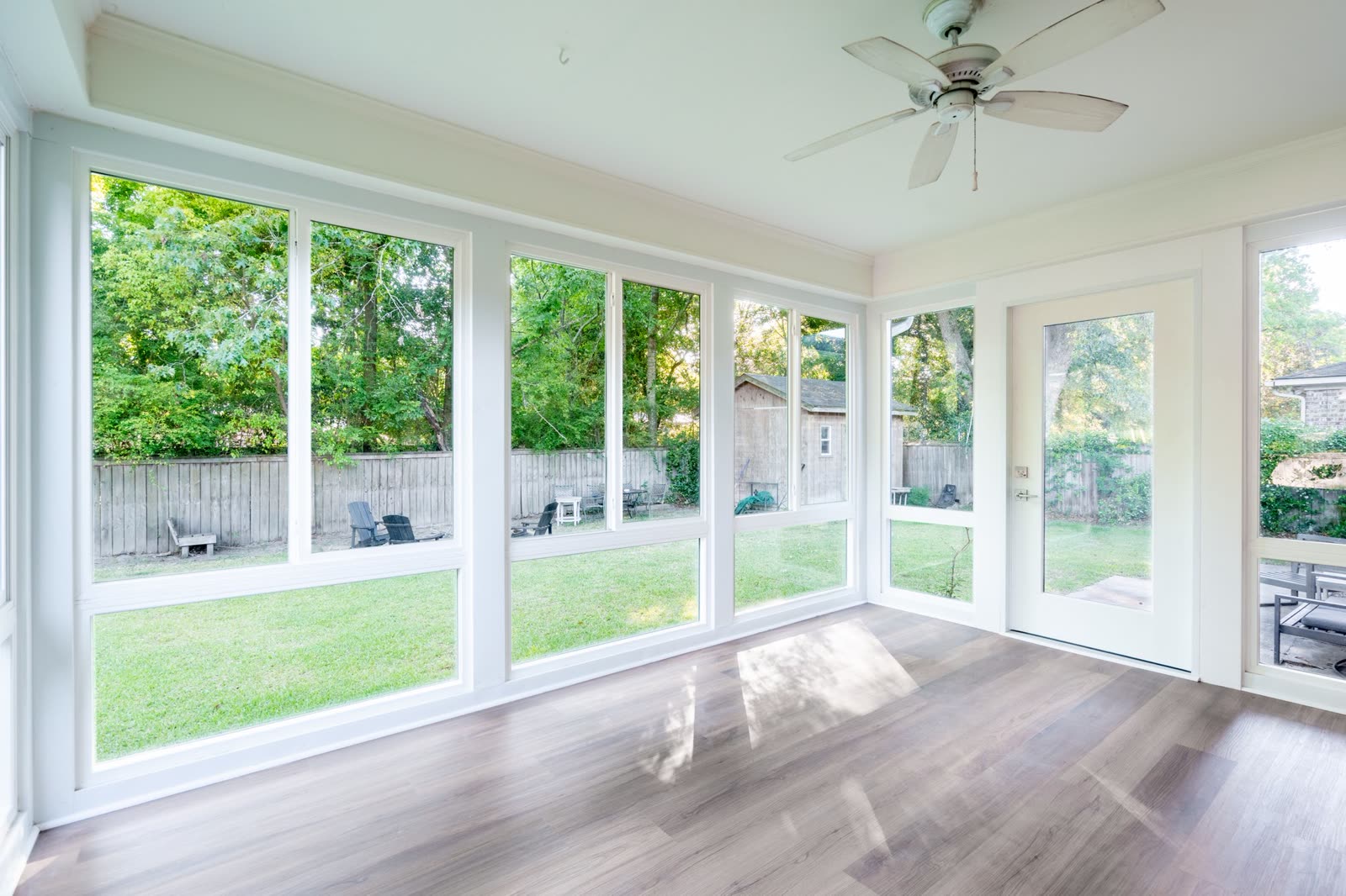 Interior of a Muhler Any-Season Room finished in insulating glass, with sliding windows above fixed lites and a glass door to the back yard
